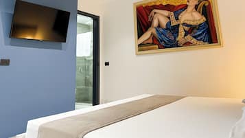 A modern bedroom with a large bed, a flat-screen TV mounted on the wall, and a painting above the bed.