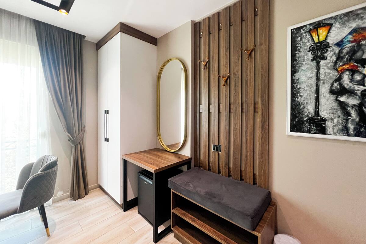Een moderne kamer met een houten bankje, een klein tafeltje, een spiegel en een wandlamp.