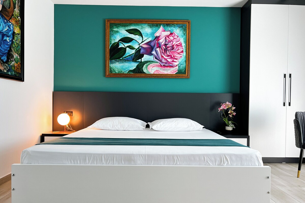 Une chambre à coucher moderne avec un lit, une table de chevet avec une lampe, un tableau et une armoire.