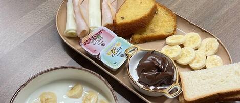 Una bandeja con un bol de batido de plátano, crema de chocolate y rodajas de plátano sobre una mesa de madera.