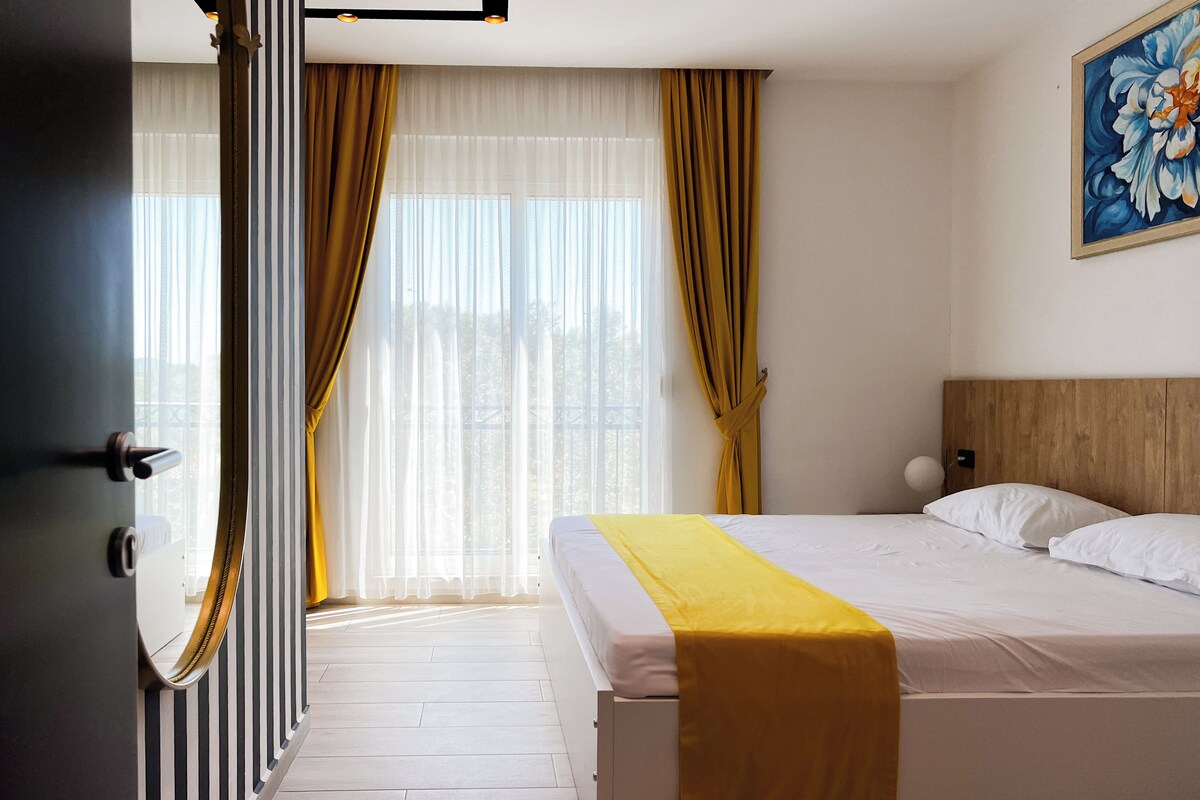 Ein Hotelzimmer mit einem Bett, einem Holz-Kopfteil, einer gelben Tagesdecke und einem Gemälde an der Wand.