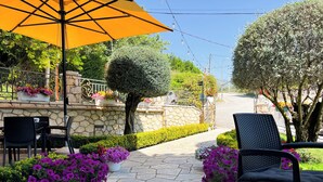 An outdoor patio with stone flooring, potted purple flowers, and black chairs. - Jata Hotel (Tirana)