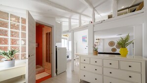 Un interior moderno con un armario blanco, una planta en maceta y una puerta de madera que da a un baño.