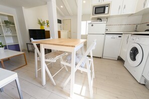 Una cocina moderna con electrodomésticos blancos, una mesa de comedor de madera y una lavadora.