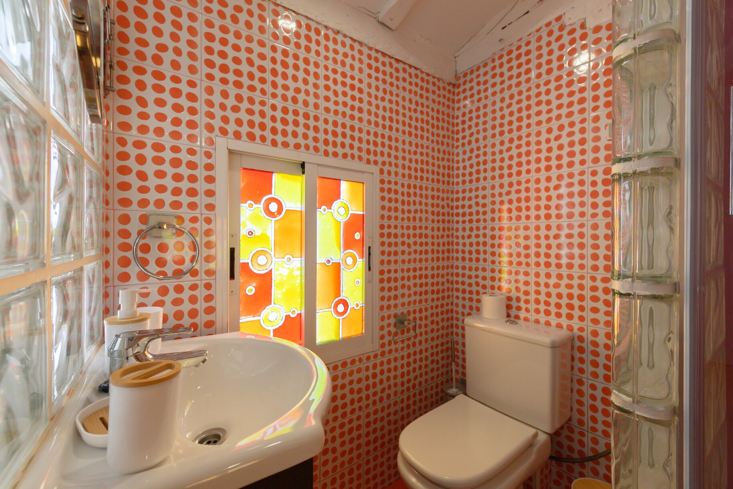 A bathroom with a polka dot tile pattern, a white sink with a wooden handle, and a toilet.