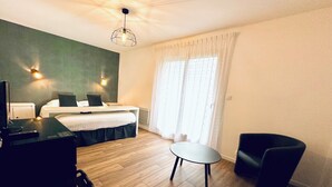 A hotel room with a bed, a desk with a chair, a small table, and a ceiling light fixture. - les chambres du bout du monde (Landévennec)