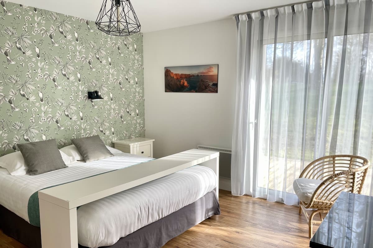 A bedroom with a bed, bedside tables, a chair, a painting, and a window with curtains.