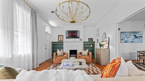 A living room with a fireplace, two sofas, a coffee table, and a TV mounted above the fireplace. - Downtown Elegant Home w/ Grill Near Riverwalk (Columbus)