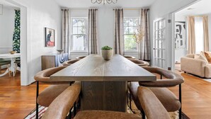 A spacious dining area with a long wooden table, cushioned chairs, and a chandelier. - Downtown Elegant Home w/ Grill Near Riverwalk (Columbus)