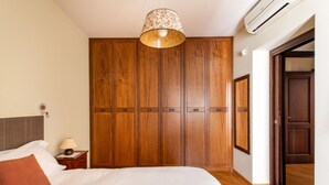 Une chambre à coucher avec un grand lit, une armoire en bois et une lampe suspendue.