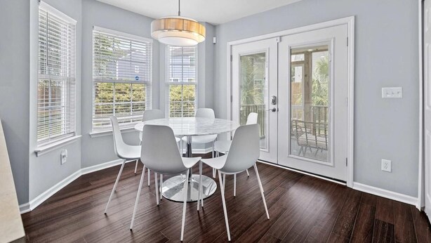 A dining area with a round table, white chairs, and a pendant light.