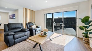 Uma sala de estar moderna com sofá, mesa de centro e porta de vidro deslizante que dá para uma área externa.