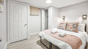 Une chambre à coucher avec un lit, une porte, un luminaire et une lampe fixée au mur.