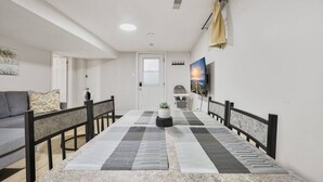 Un salon moderne comprenant une table à manger, un canapé et un téléviseur fixé au mur.