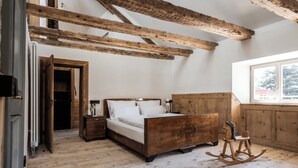 Un dormitorio con una cama de madera, una mecedora y vigas de madera a la vista.
