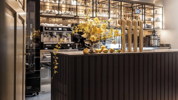 Una cocina moderna con una isla central, electrodomésticos integrados y un jarrón decorativo con flores.