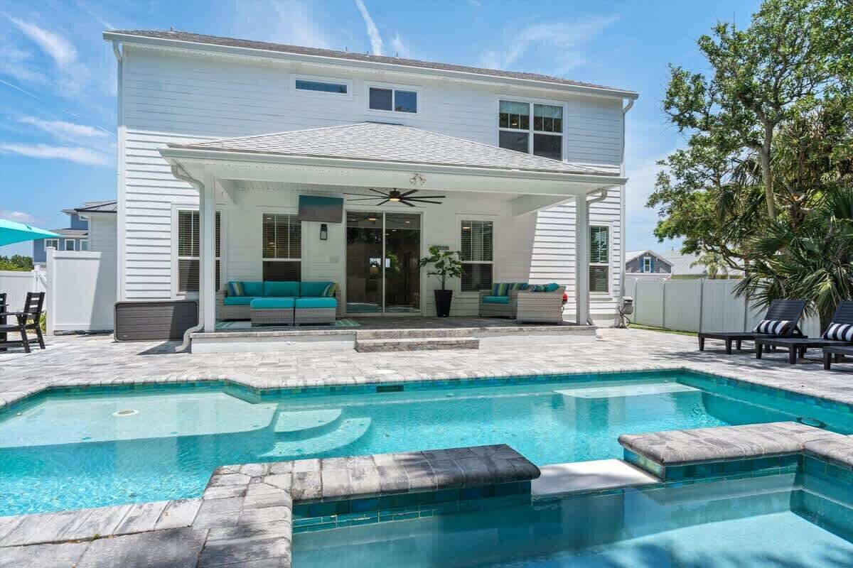 Une maison à deux étages dotée d’un patio couvert et d’une piscine.
