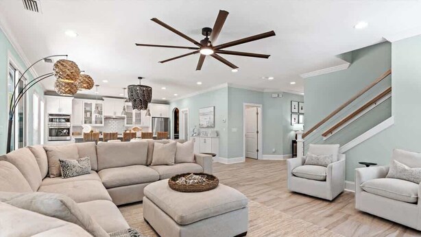 A spacious living room with a sectional sofa, a round ottoman, and a ceiling fan. - Luxury Oasis Heated Pool, Game Rm, 3 Blks to Beach (St. Augustine)