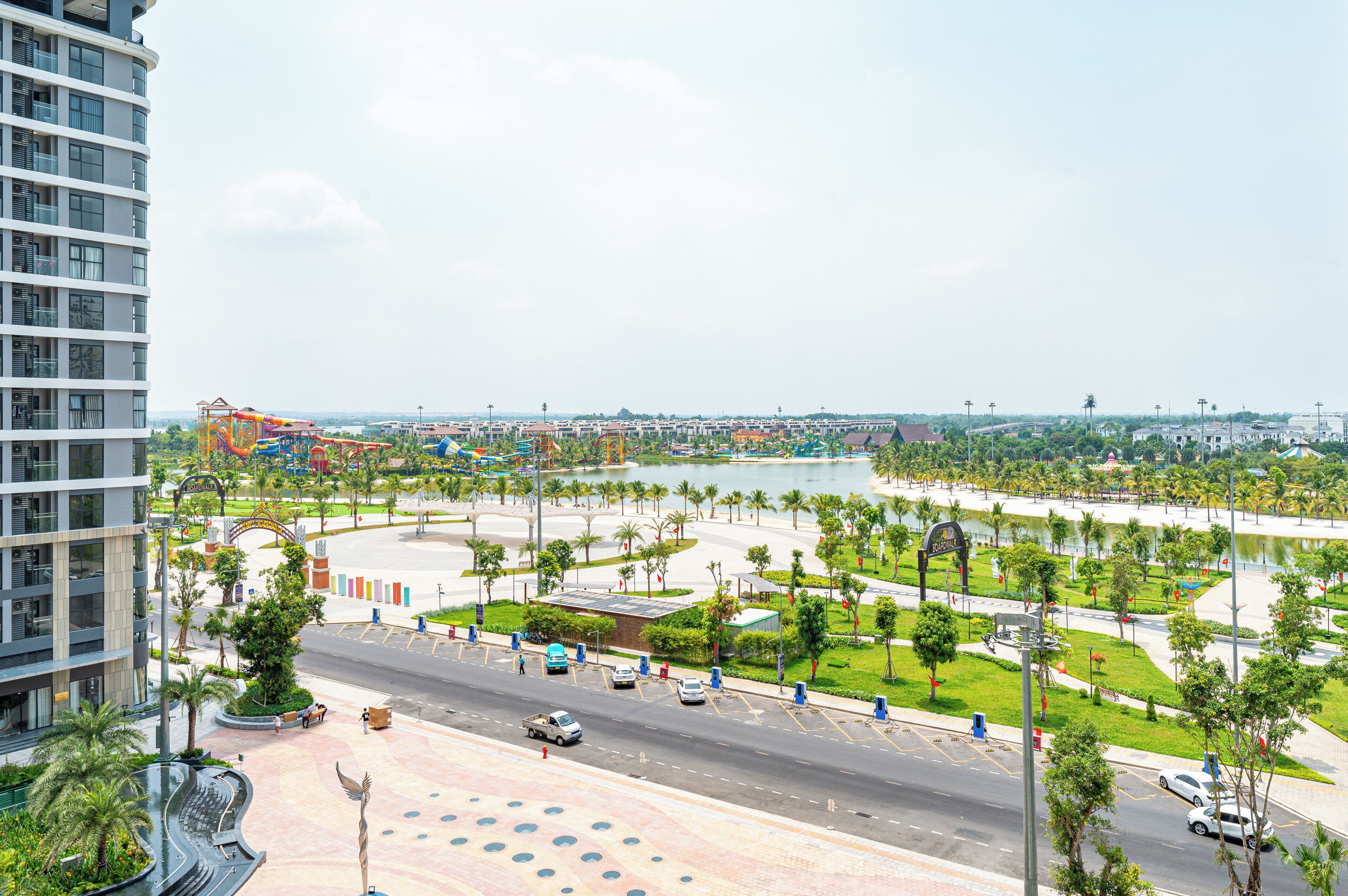 A modern urban area with a road, parking, and a water body.
