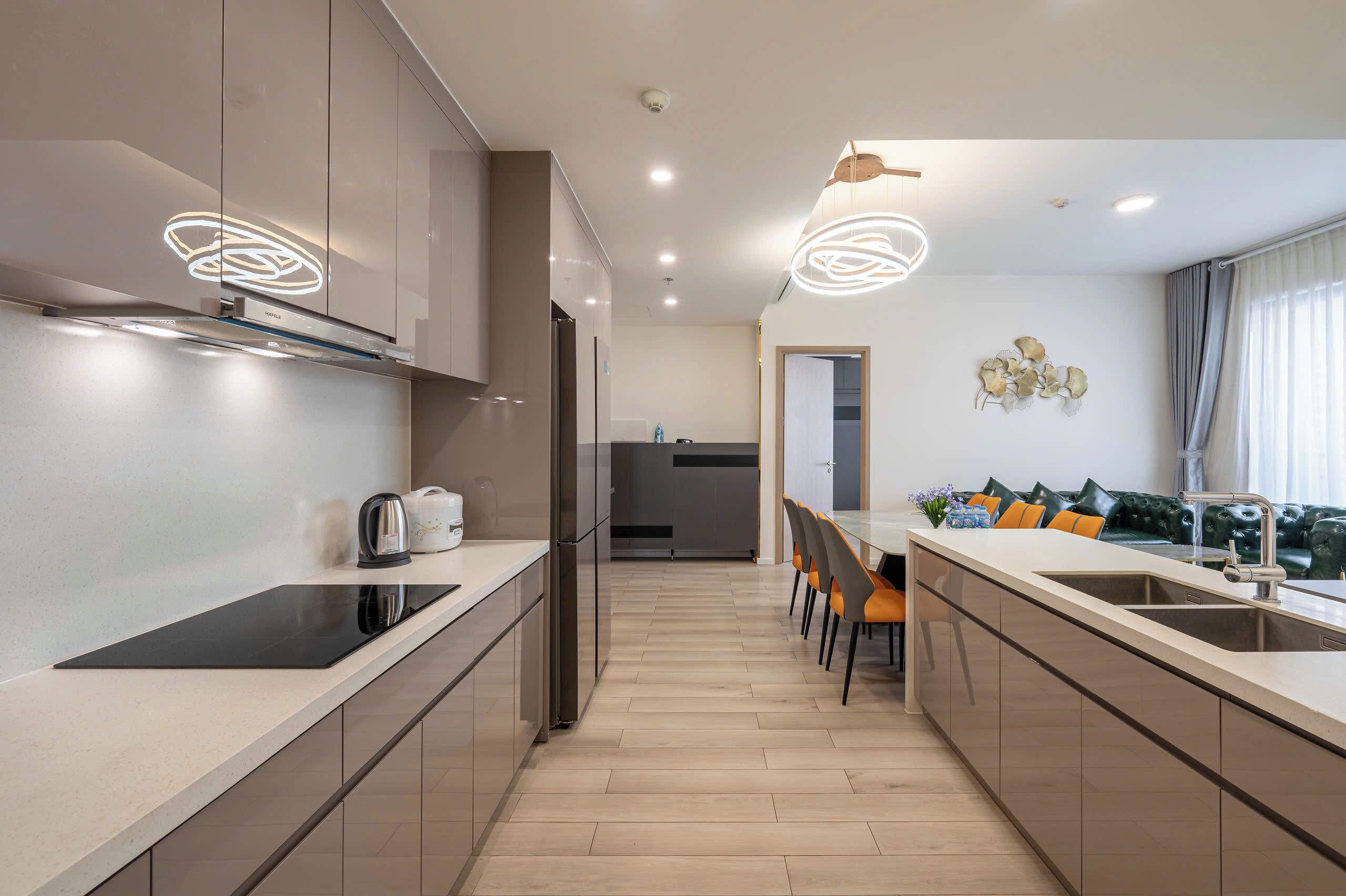 Una cocina moderna con una isla central, electrodomésticos de acero inoxidable y un comedor con sofá y sillas.