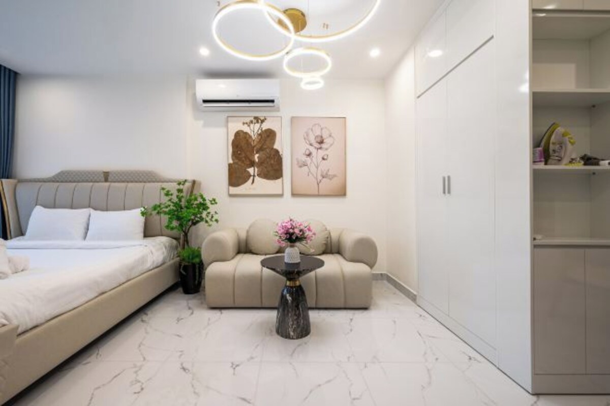 A modern bedroom with a bed, sofa, and a small table with a vase.