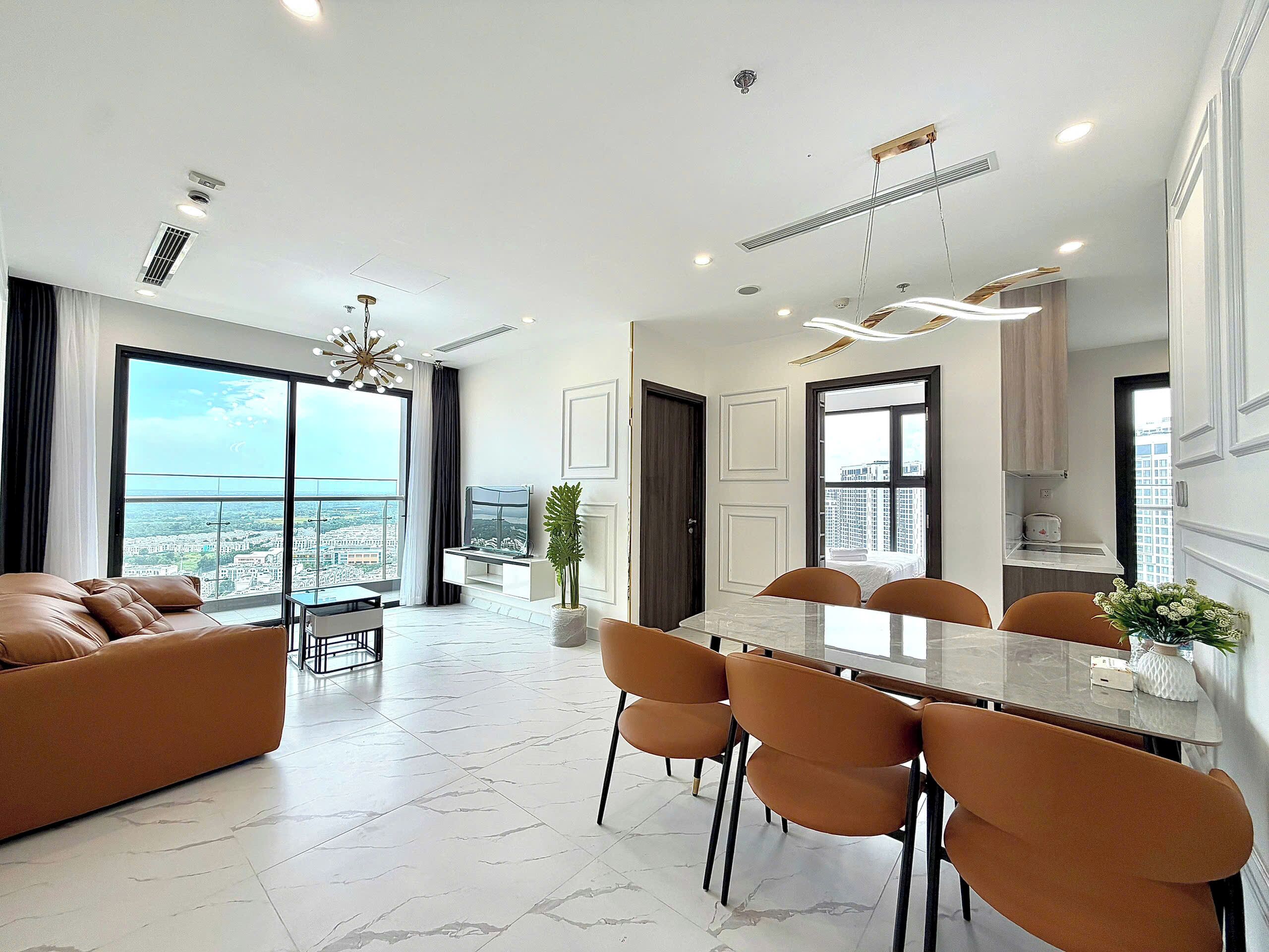 A modern apartment with a dining area, kitchen, and a large window with a city view.