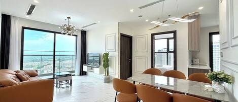 A modern apartment with a dining area, kitchen, and a large window with a city view.