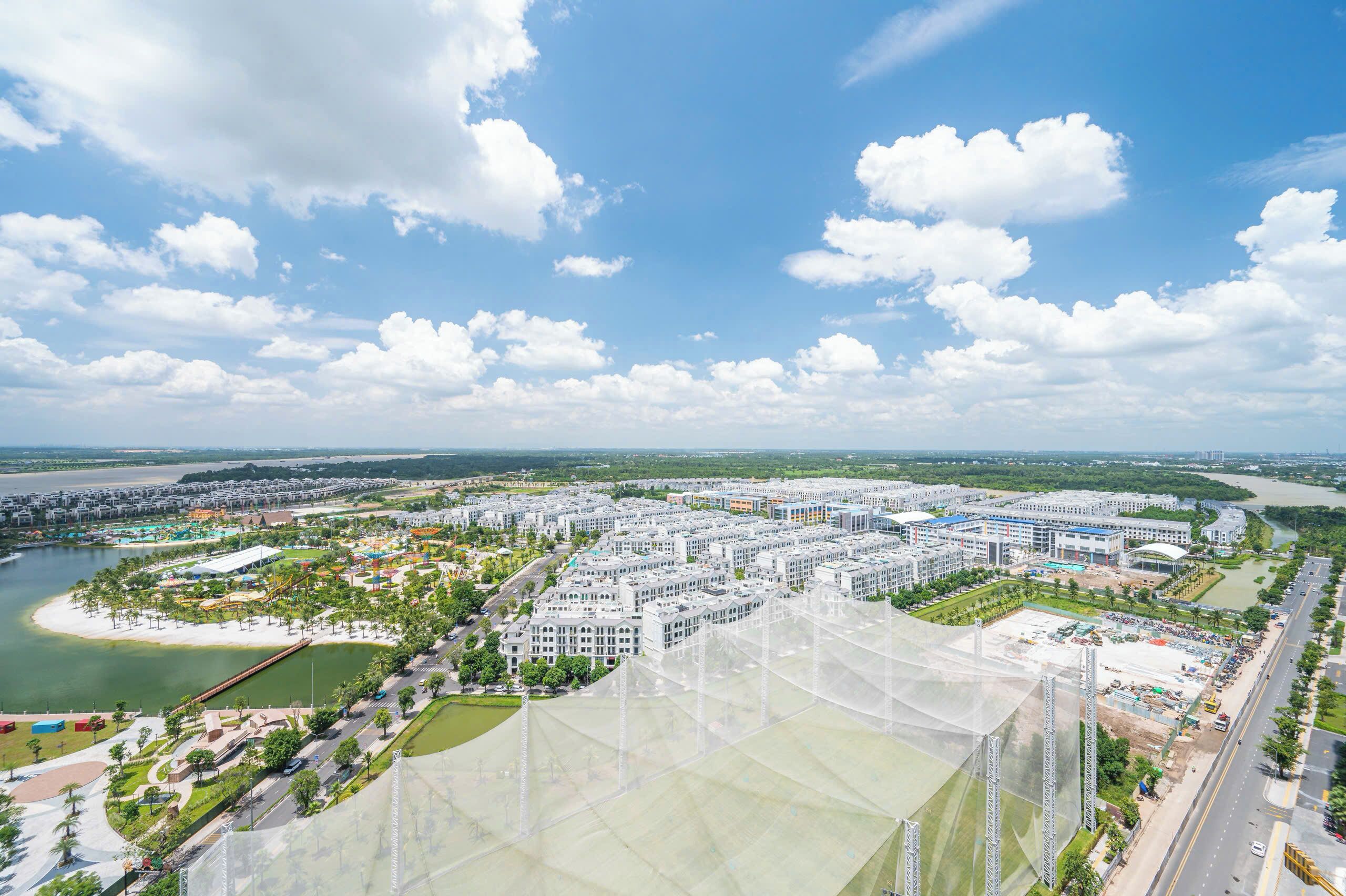 An aerial view of a modern urban area with a river, a large open park, and several buildings.