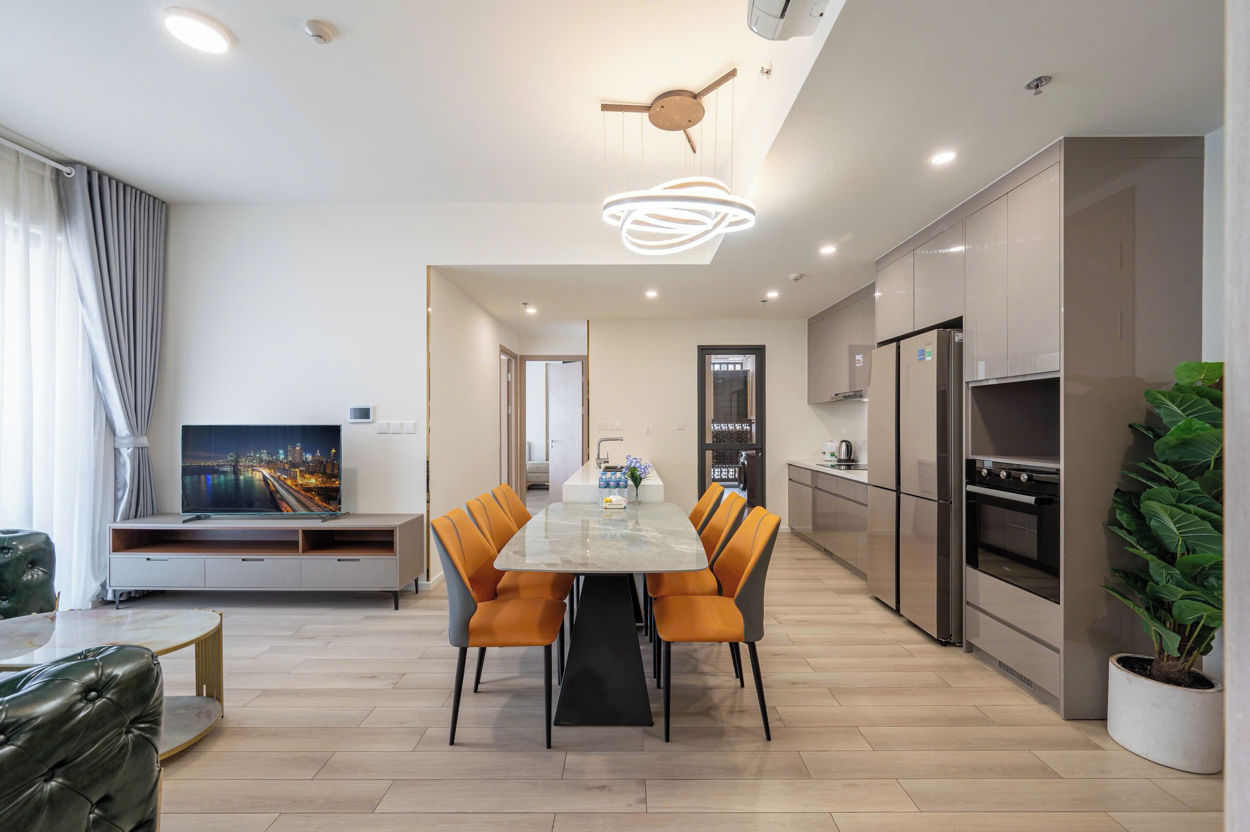 A modern kitchen with a dining area, featuring a large island, built-in appliances, and a ceiling fan.