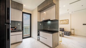 A modern kitchen with built-in appliances, a large window, and a view of the city. - Studio - GH5 - Vinhomes Grand Park (Ho Chi Minh City)