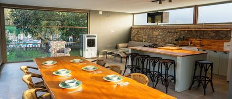 A modern kitchen with a large island, bar stools, and a dining area with a long wooden table set for six.