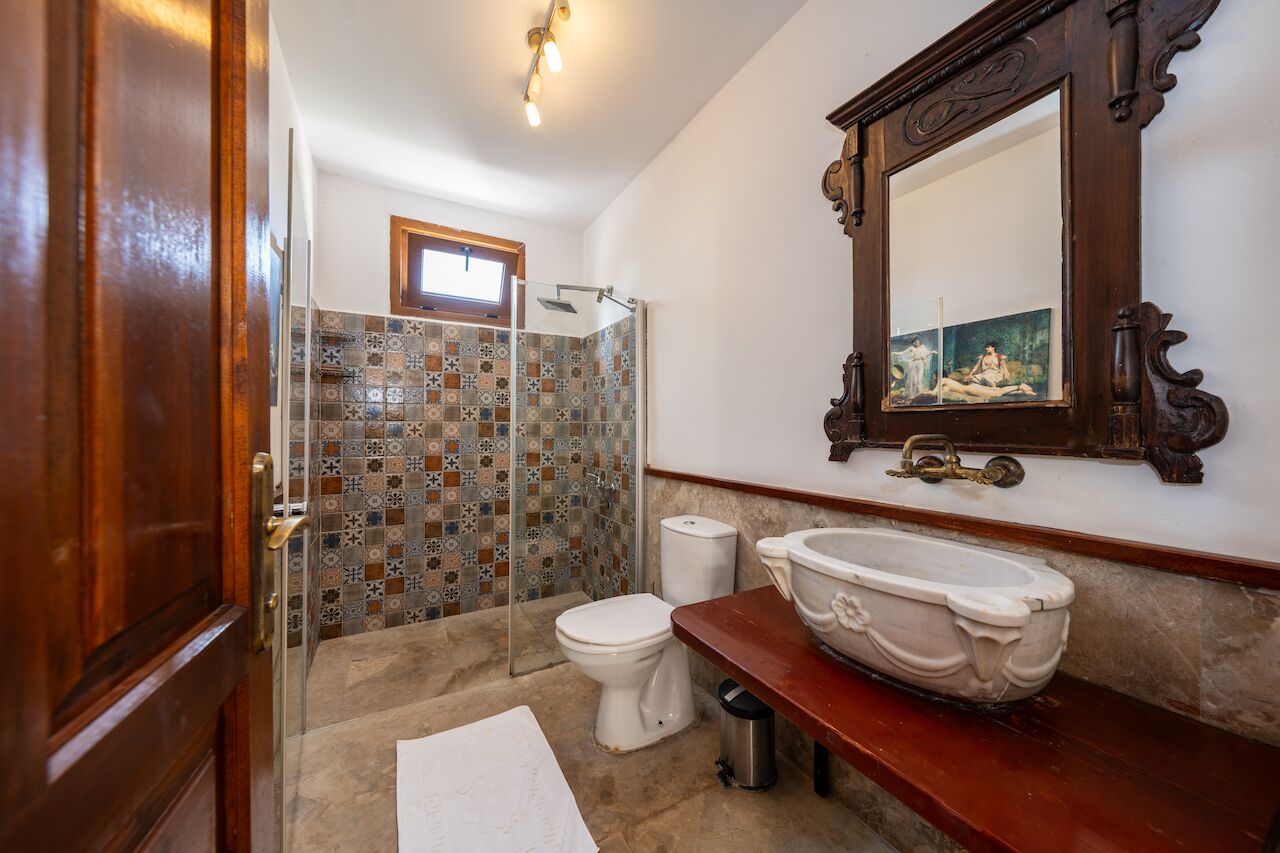 A bathroom with a shower, toilet, and sink, featuring a tiled shower area and a large mirror above the sink.