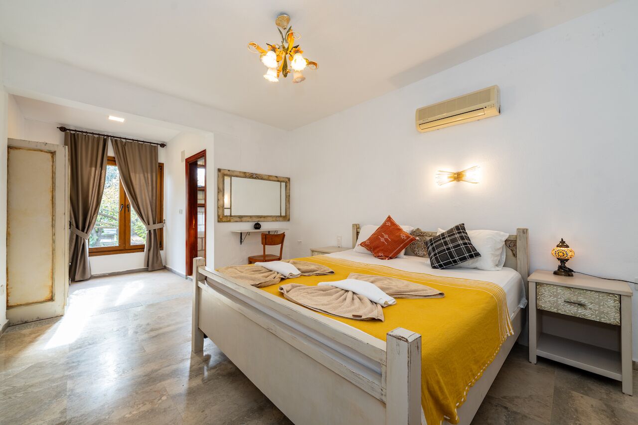 A hotel room with a bed, bedside table, and a mirror.