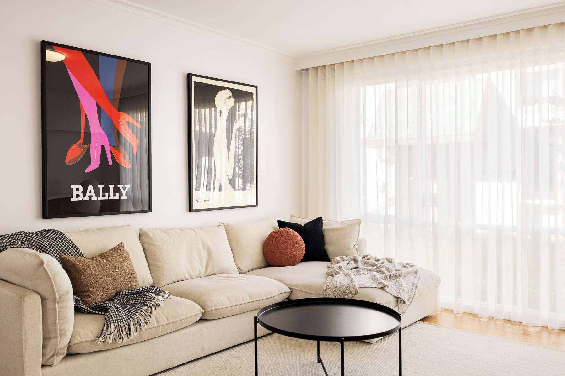 A living room with a sofa, a coffee table, and two framed artworks on the wall.