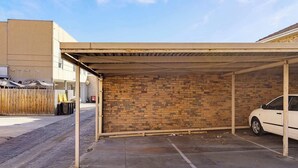 A covered parking area with a brick wall and a car parked inside.