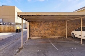 A covered parking area with a brick wall and a car parked inside.
