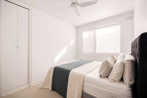 Una camera da letto con un letto, una finestra, una ventola a soffitto e un armadio.