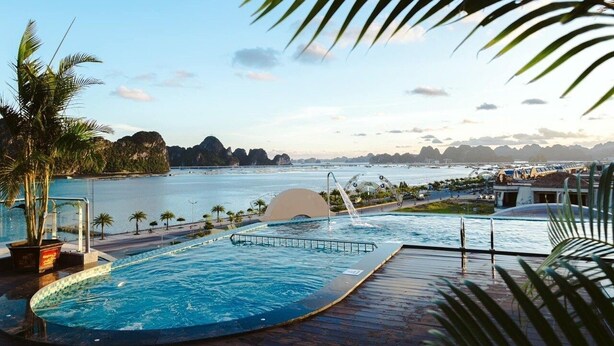 Piscina con vista al mar y montañas a lo lejos.