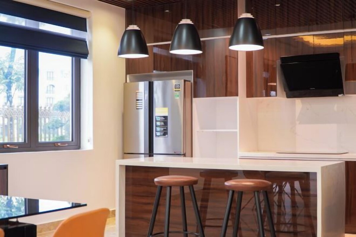 A modern kitchen with a built-in refrigerator, a flat-screen TV, and a bar area with stools.