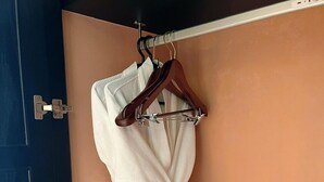 Un albornoz blanco colgado de una percha de madera en una habitación con una puerta azul y paredes color melocotón.
