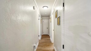 En smal gang med hvide vægge, trægulv og en loftlampe.