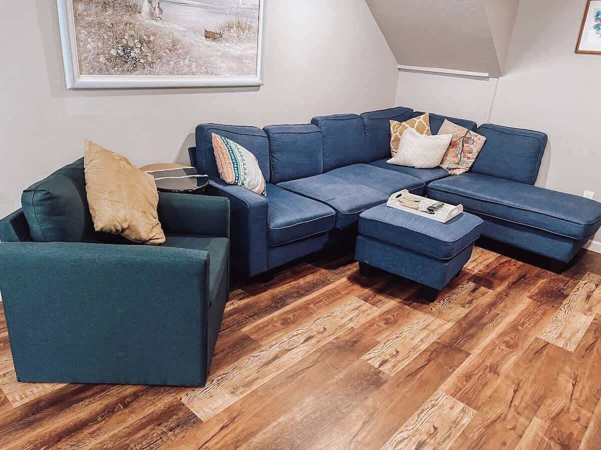 Ein modernes Wohnzimmer mit einem Ecksofa, einer Liege und einem passenden Ottomanen.
