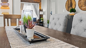 A dining area with a wooden table, a potted plant, and a modern chair. - Riverview Retreat Only 1 Mi Downtown Louisville! (Jeffersonville)