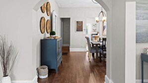 A hallway with a wooden floor, a blue cabinet, and a dining area with a table and chairs. - Walkable Historic District 1 Mi to Downtown Lou! (Jeffersonville)