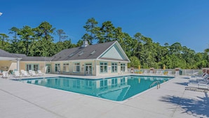 Une piscine avec des chaises longues et un bâtiment doté d’un toit en pente.