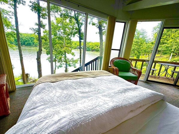 Une chambre avec un grand lit, une vue sur un lac et un balcon équipé d  ’une chaise.