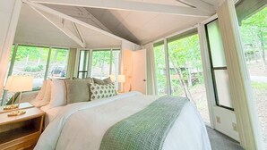 Una camera da letto con un letto grande, un comodino e una finestra vista alberi.