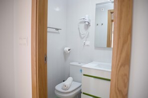 Un baño con inodoro, toalla, secador de pelo y espejo.