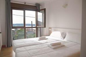 Habitación de hotel con una cama grande, vistas de la ciudad a través de una ventana y suelo de madera.