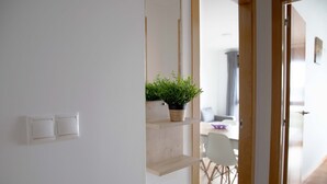 A modern interior with a white wall, a wooden door, and a plant on a shelf.